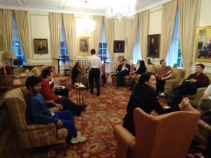 Student members sat in arm chair in a large circle finding out who did it during the reception